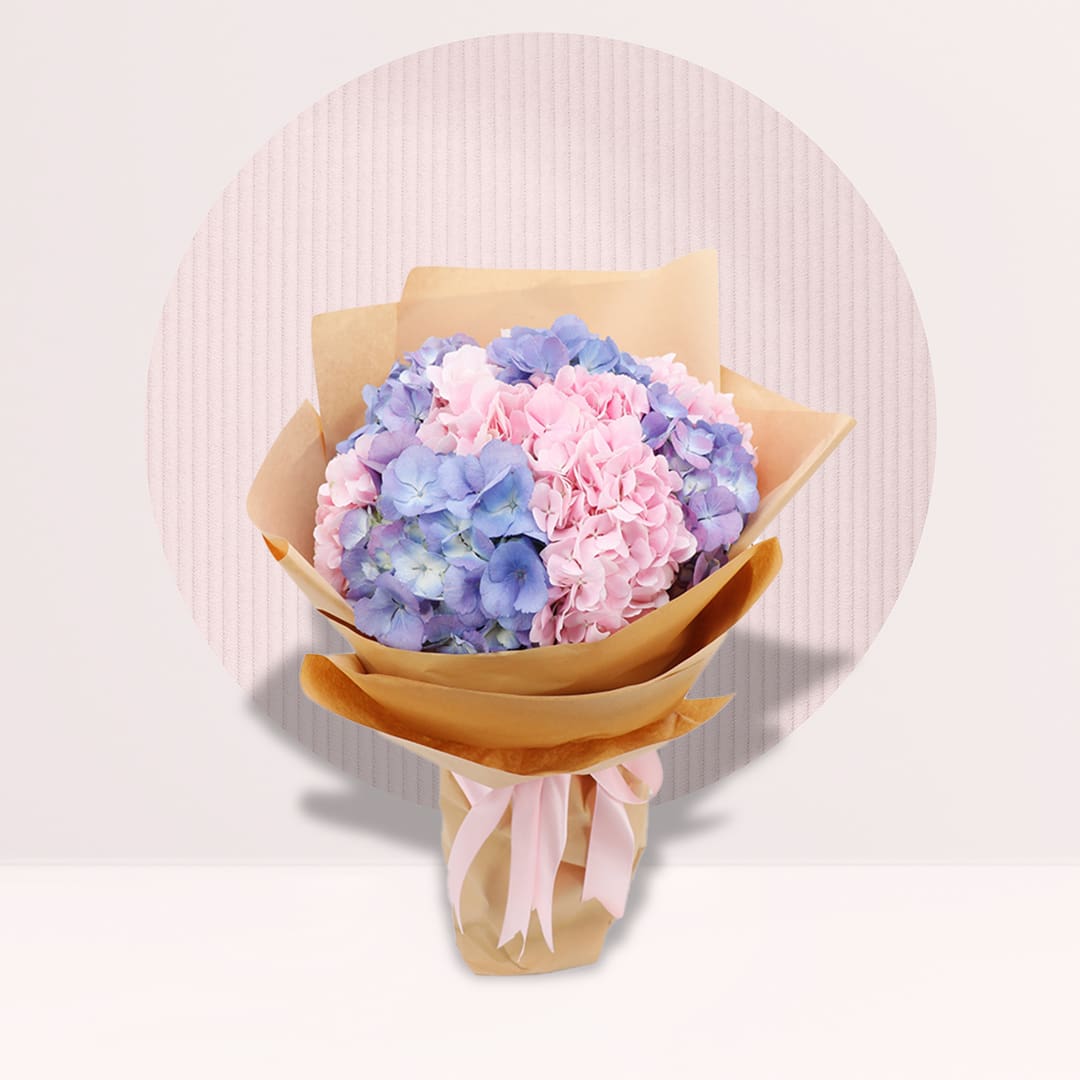 1 (11) Blue and pink hydrangea bouquet with pastel blooms and neutral wrapping.