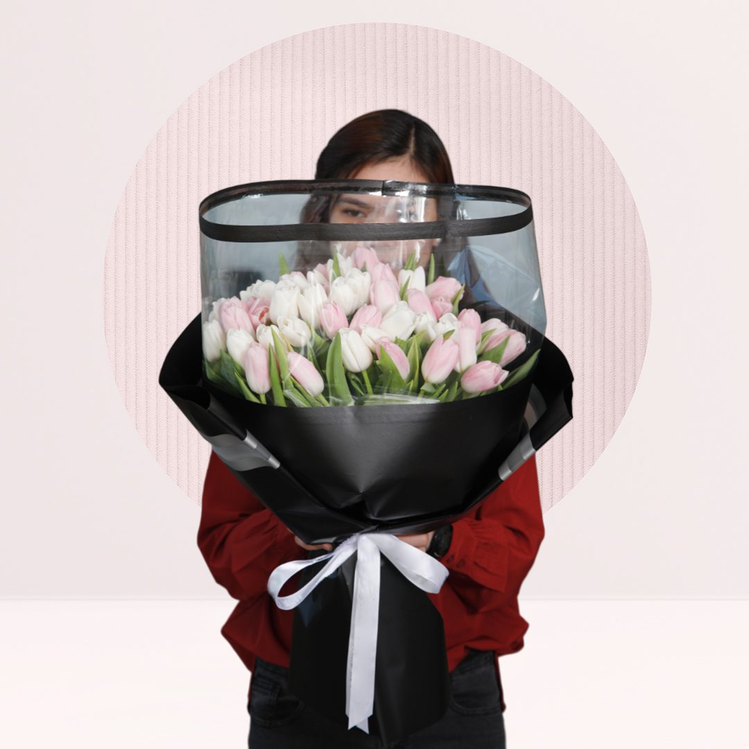 1 white and pink tulips stems wrapped in a black wrap tied with a white ribbon