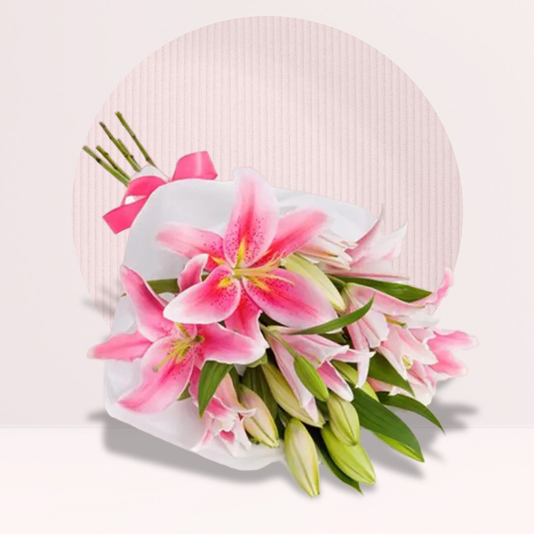Fresh pink lily bouquet with green leaves in white wrapping and a pink ribbon.