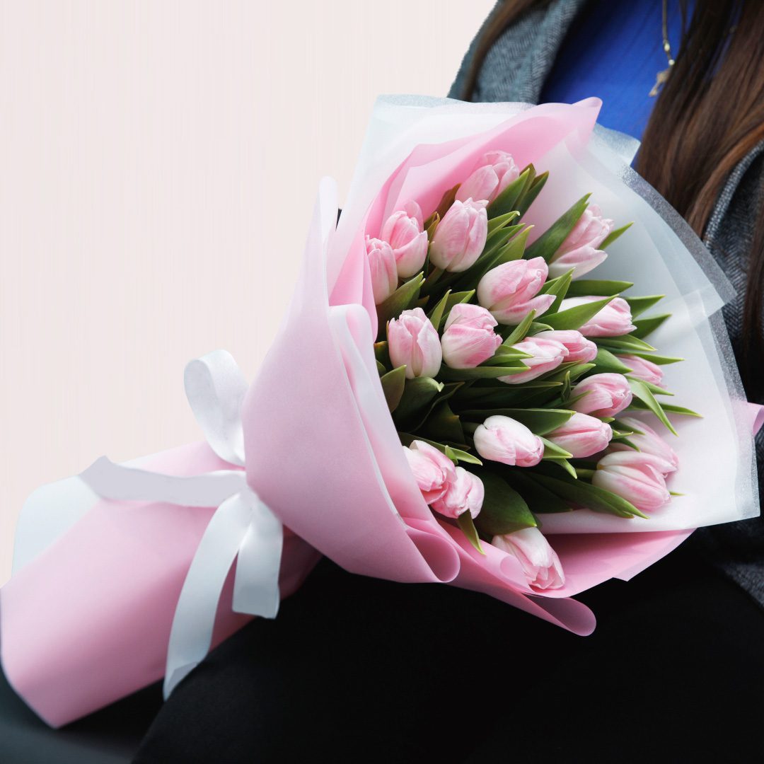 Pink Tulips-01 A woman smiling while holding a vibrant bouquet of pink tulips in her hands