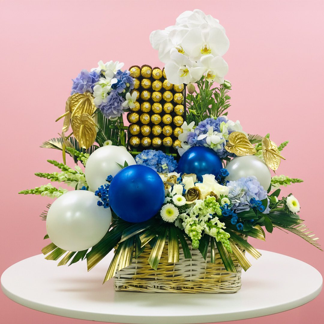 Magical-Blues-with-Ferrero-Rocher-15-10 A basket filled with blue and white flowers alongside colorful balloons, creating a festive and cheerful display.