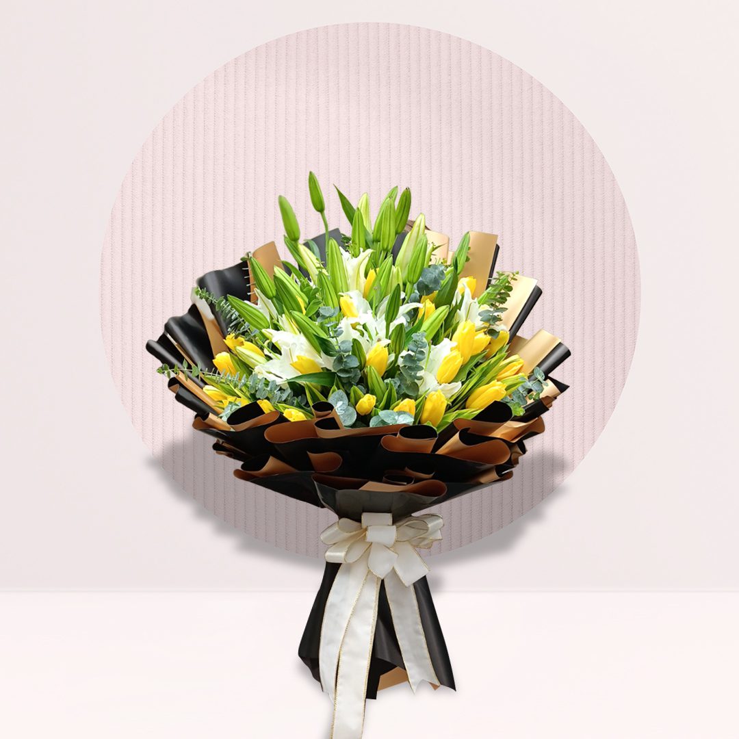 Hand bouquet of yellow tulips and white lilies with fresh greenery.