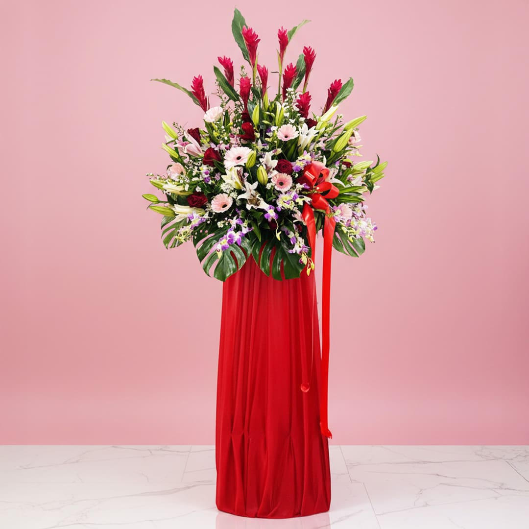 Exotic Bloom Stand A decorative red vase with a floral arrangement and ribbon, designed for a grand opening stand display.