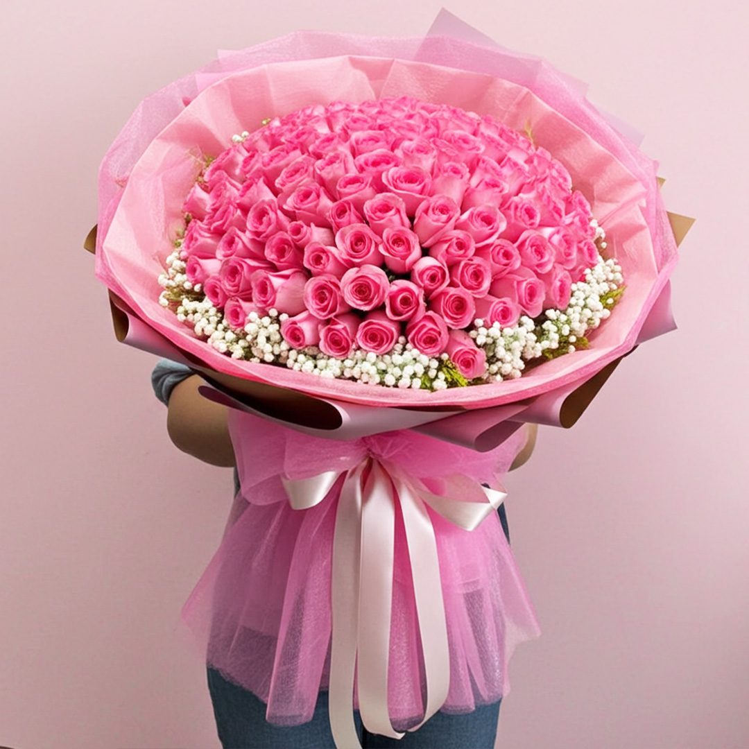 02 A woman stands holding a large bouquet of pink roses, showcasing their lush blooms and green foliage.