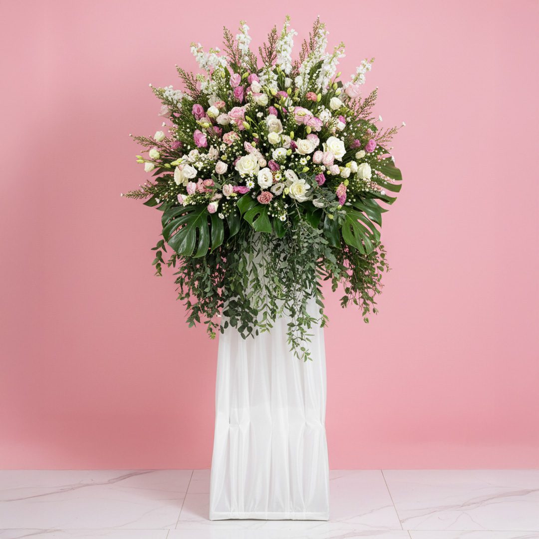 Lavender Adieu-01-12-11 A floral wreath composed of purple and white blooms, elegantly positioned on a stand.