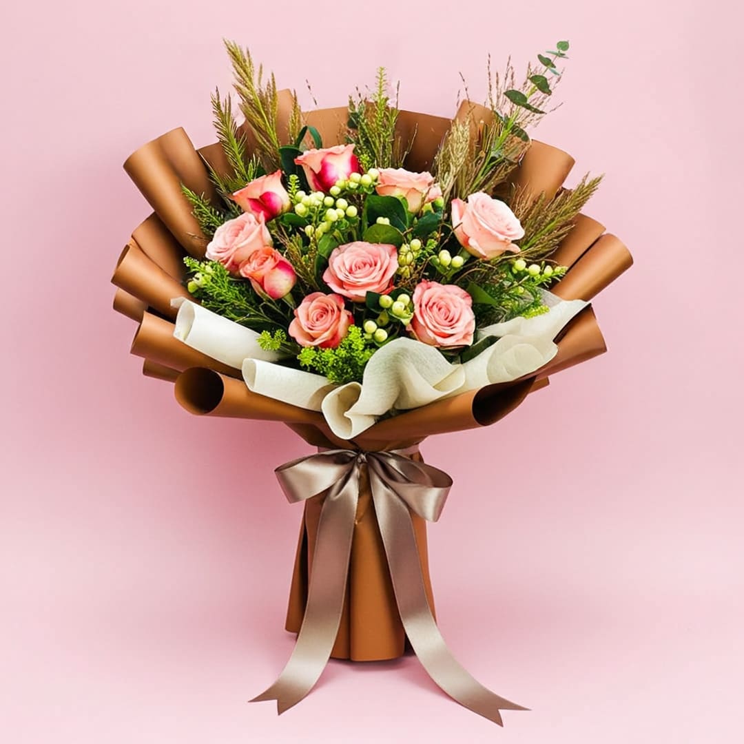 Elegant Cappuccino Roses-01 A vibrant bouquet of roses tied with a ribbon, set against a soft pink background.
