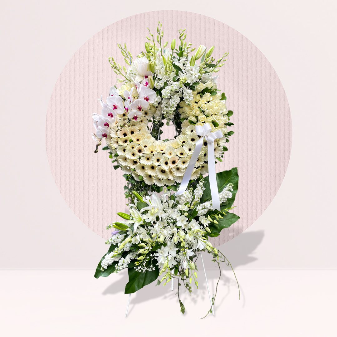 Floral Wreath: The arrangement features a circular wreath at the top, made of white flowers, possibly daisies, gerbera daisies, or chrysanthemums.