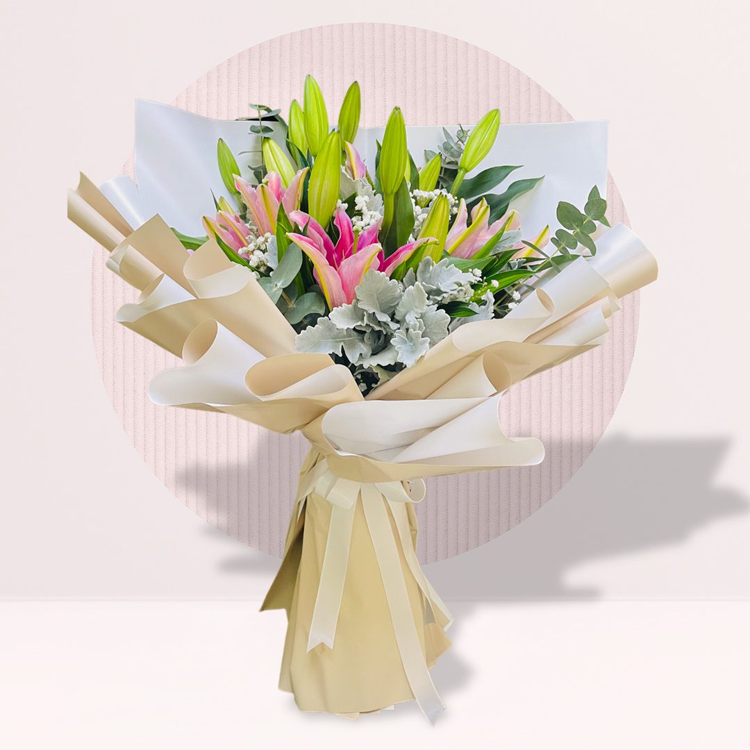 A bouquet of pink and white lilies with green stems, wrapped in cream and white paper, tied with a ribbon,
