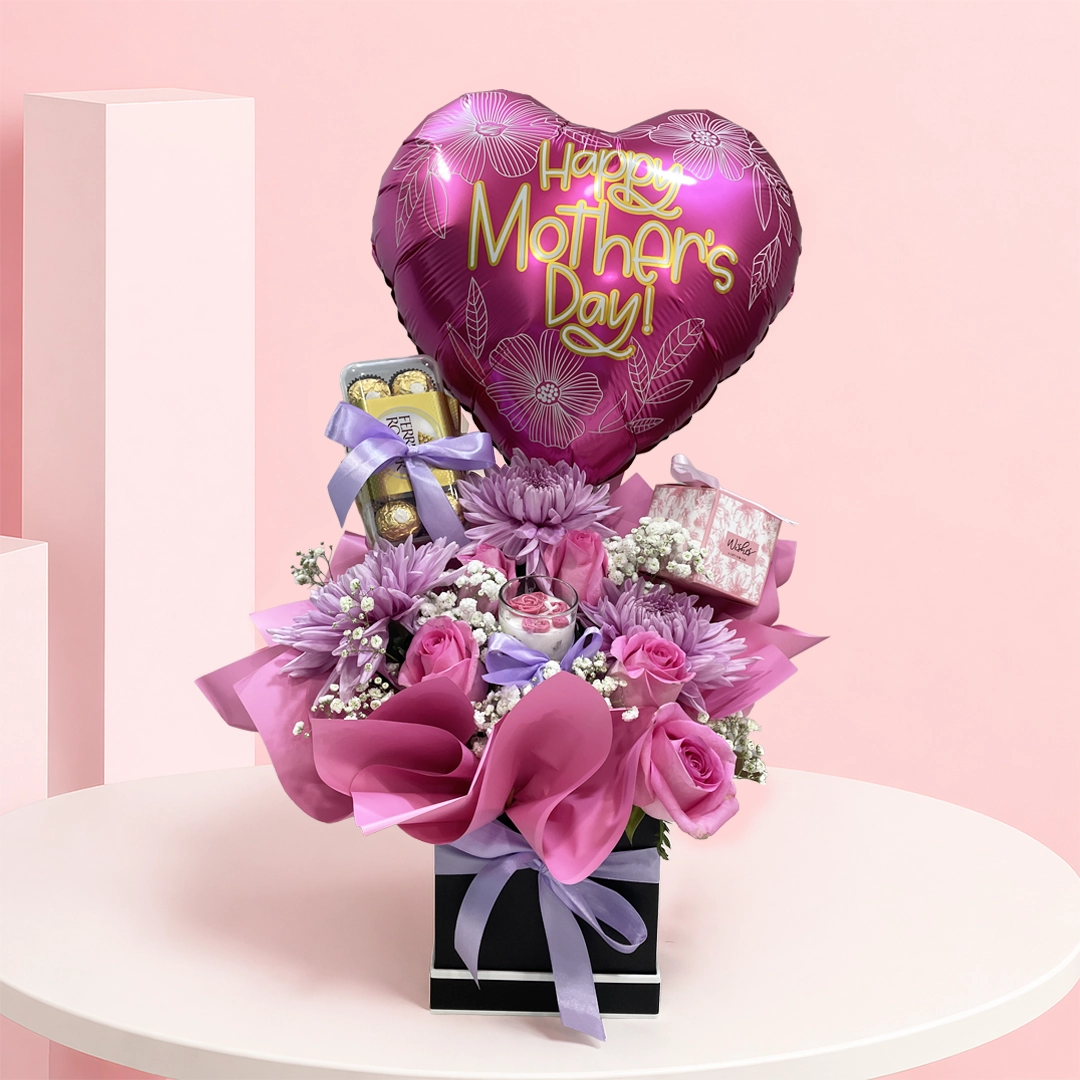 moms-radiance-box_2026 A luxurious arrangement of lavender chrysanthemums and roses with a scented candle, designed to brighten her space and heart.