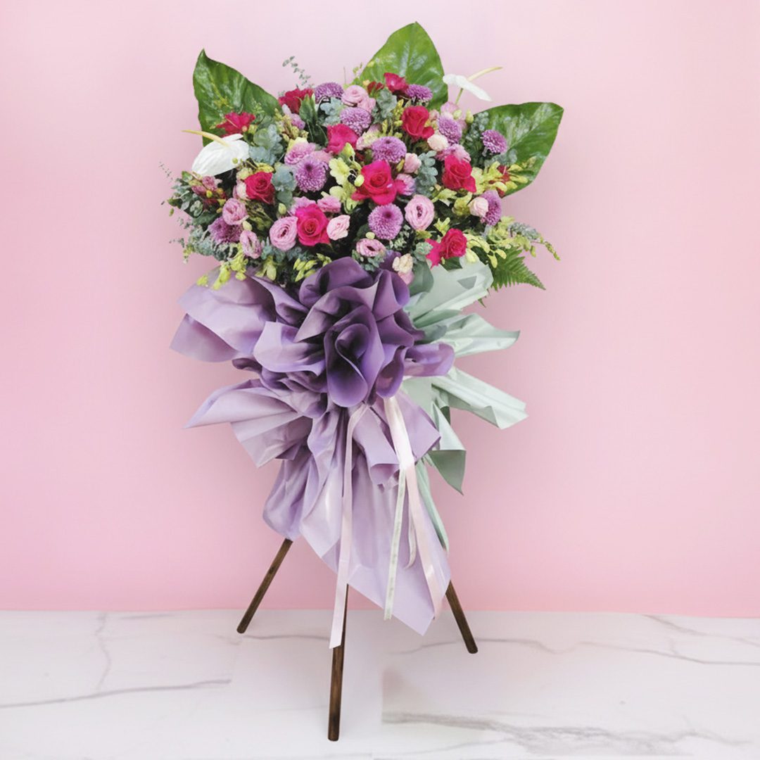 01 celebration flower stand with pink and purple roses, chrysanthemums, and a lavender ribbon.