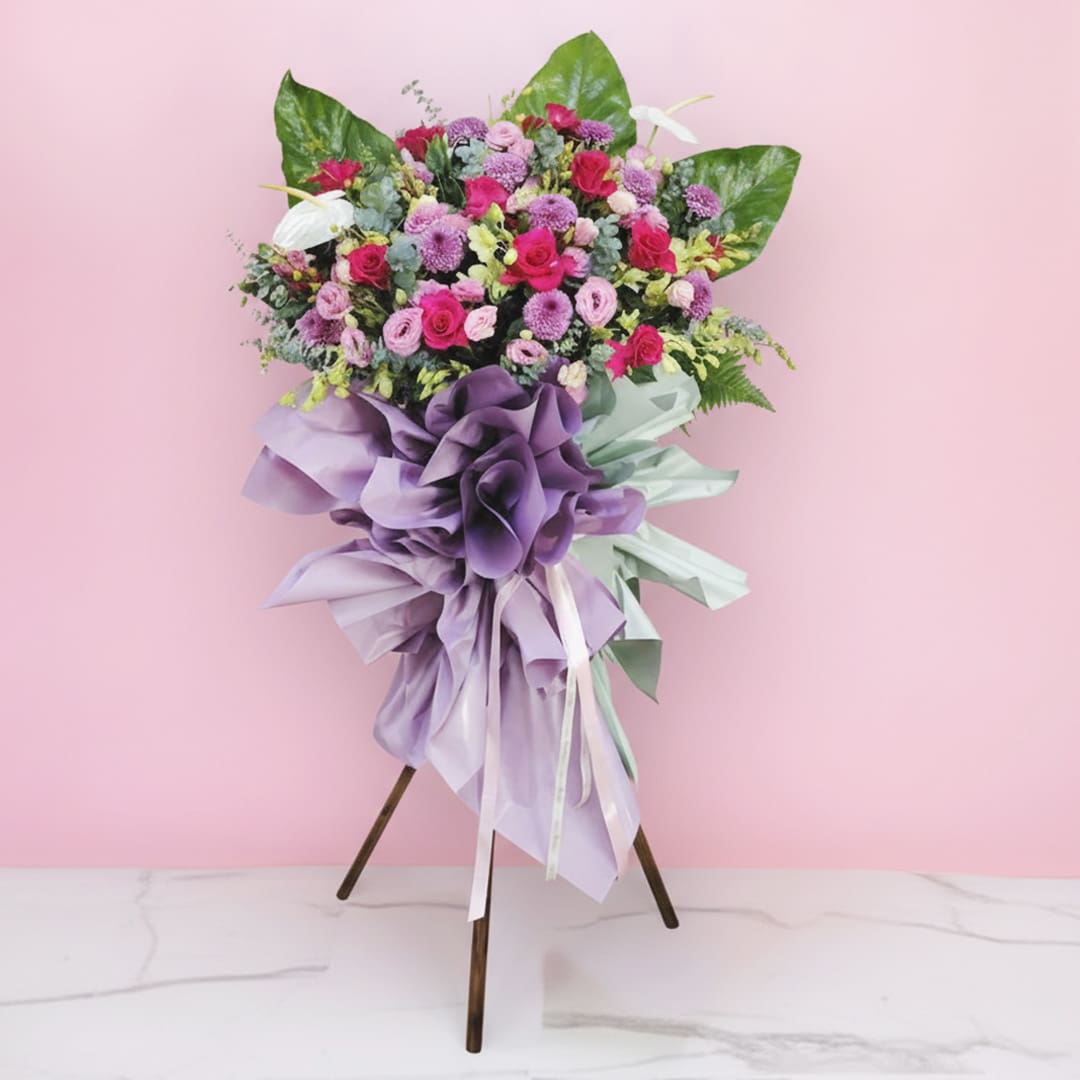 01 celebration flower stand with pink and purple roses, chrysanthemums, and a lavender ribbon.