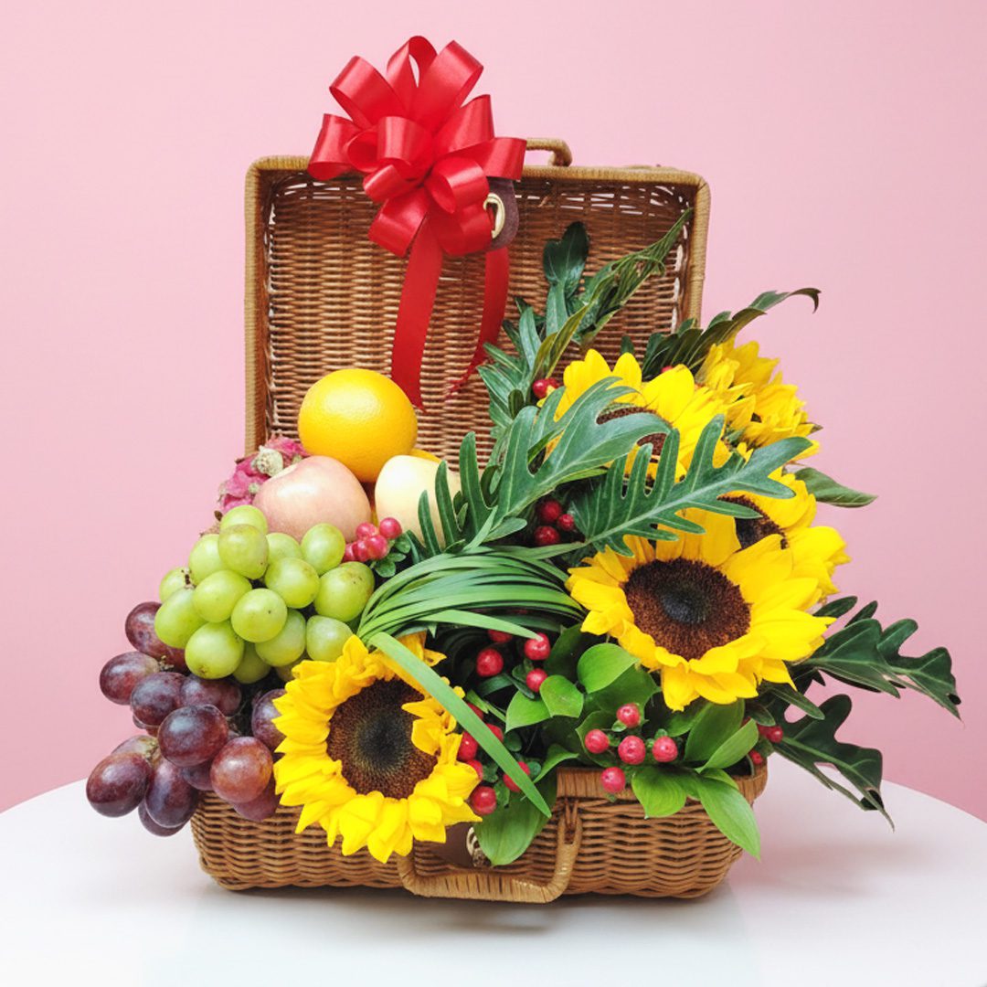 Fruit and flower basket with sunflowers, grapes, apples, and a red bow in a wicker hamper.