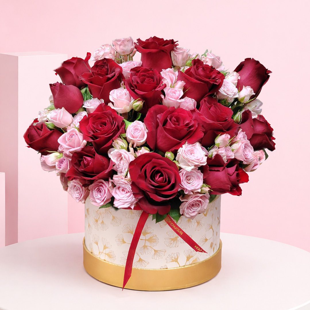 01 Rose Duo Box Deep with red roses and soft pink spray roses in a premium white-and-gold hatbox arrangement, finished with a satin ribbon.