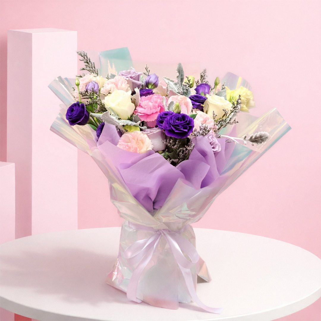01 Pastel glow bouquet with lavender, pink and white blooms wrapped in holographic shimmer paper with ribbon.