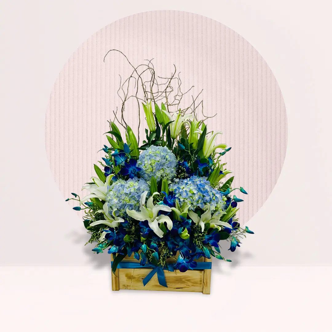 A blue and white floral arrangement displayed in a rustic wooden box.
