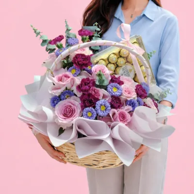 Flower basket of pink roses, carnations, purple asters and Ferrero Rocher chocolates.