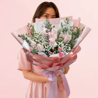 Pastel Dream Bouquet featuring pink roses, pink spray carnations, gypsophila, and ruscus leaves arranged in a romantic and elegant floral design.