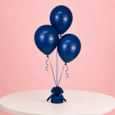 Three navy blue balloons tied with curly ribbon to a decorative weight, displayed on a white table.
