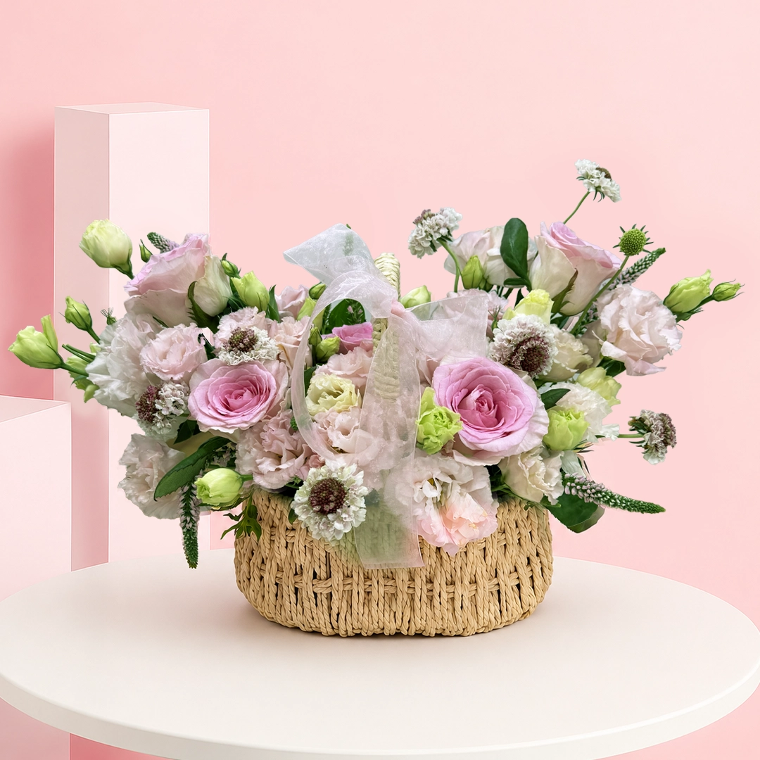 timeless-pink-rose-basket A handcrafted floral basket featuring pink roses, lisianthus, veronica, scabiosa blooms, and vibrant foliage in a naturally flowing arrangement.