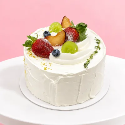 Round vanilla cake finished with smooth cream and topped with an assortment of colourful fresh fruits for a vibrant, fruity presentation.