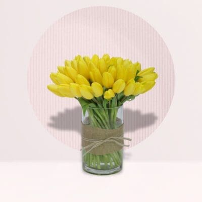Fresh yellow tulips arranged in an elegant decorative vase.