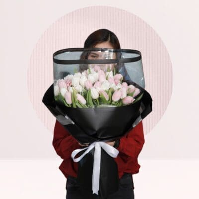 white and pink tulips stems wrapped in a black wrap tied with a white ribbon