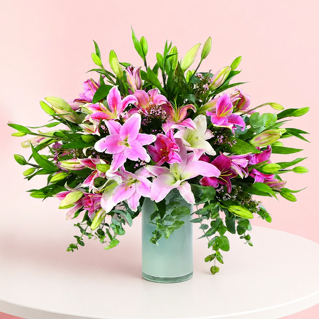 astounding-lilies_2026 A vase filled with 20 stems of Stargazer Lilies, complemented by decorative fillers for an elegant floral arrangement.
