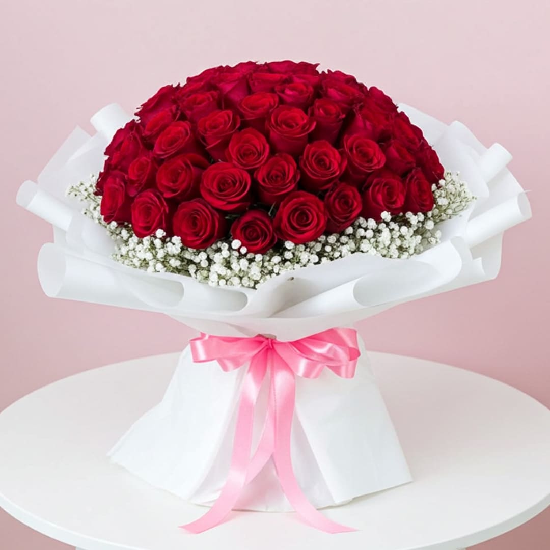 Hearts in Bloom – 99 Roses Bouquet-13-10 A vibrant bouquet of red roses surrounded by delicate sprigs of baby's breath.