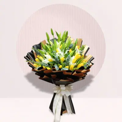 Hand bouquet of yellow tulips and white lilies with fresh greenery.