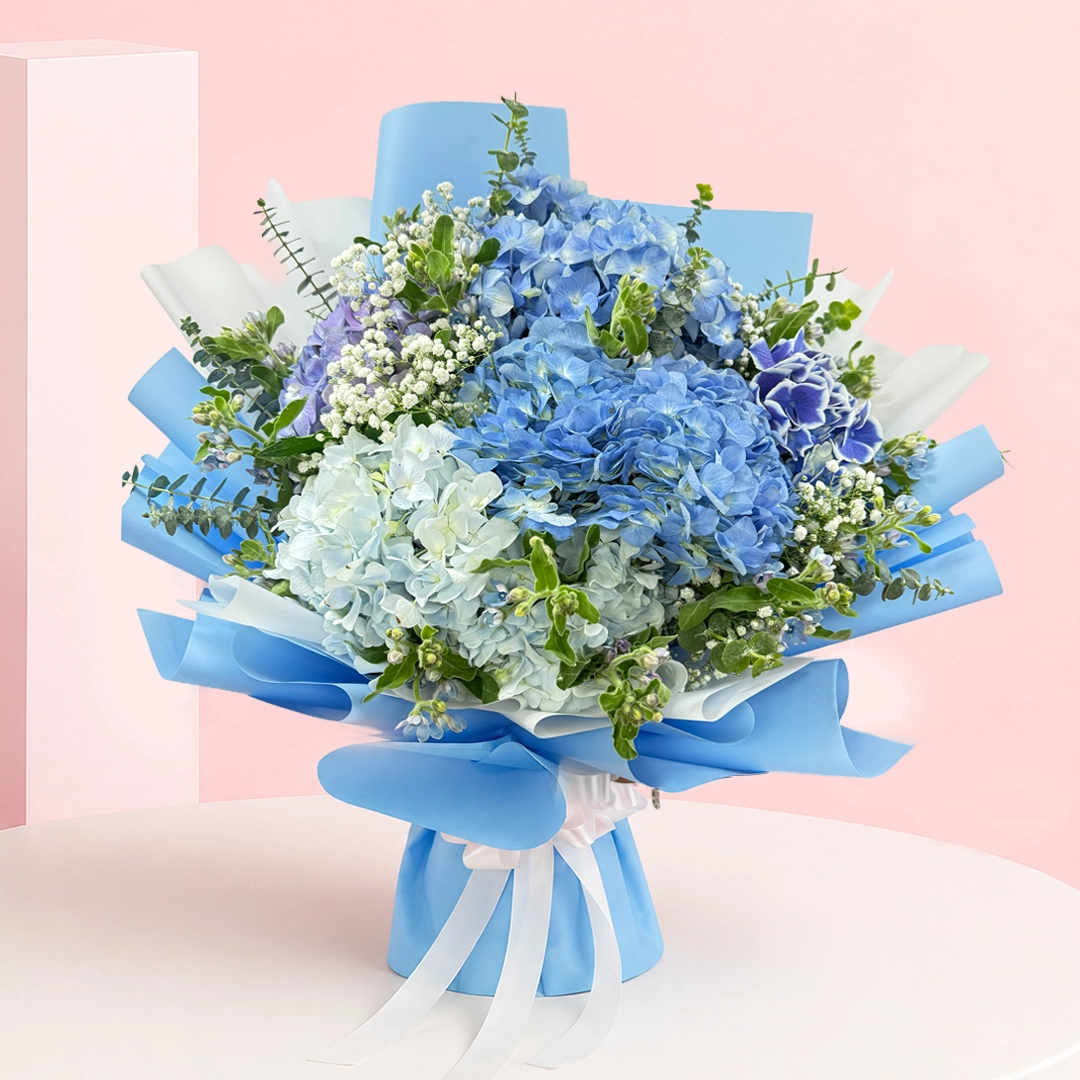 blue-hydrangea-rose-bouquet Hydrangea Breeze Bouquet featuring fresh hydrangeas, baby’s breath, and eucalyptus arranged in a soft, airy, and elegant floral design.