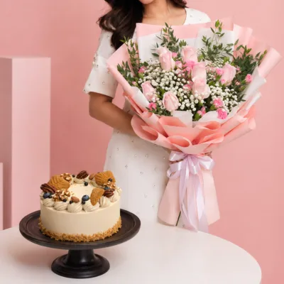 Sweet Bouquet Walnut Cake Combo featuring pink roses, pink spray carnations, gypsophila, and ruscus leaves paired with a Coffee & Walnut cake made with peanut cream and walnuts.
