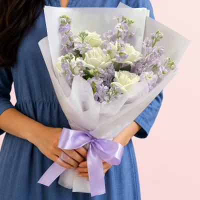 Fresh white roses paired with fragrant matthiola, beautifully wrapped in a white sheet with lush greenery and delicate fillers.